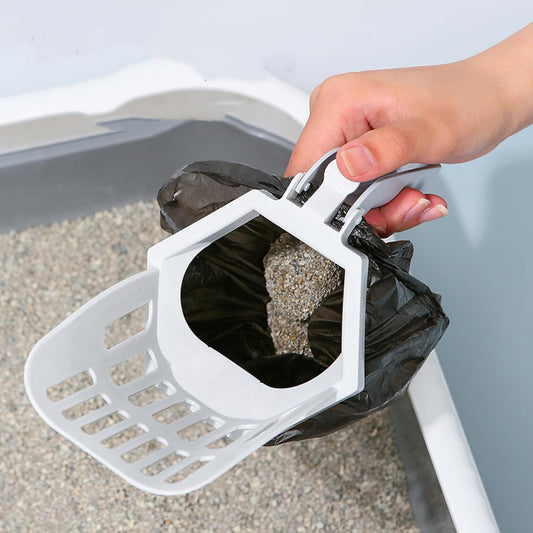 Hand holding white cat litter scoop with attached waste bag, sifting clumped litter from litter box for easy cleaning