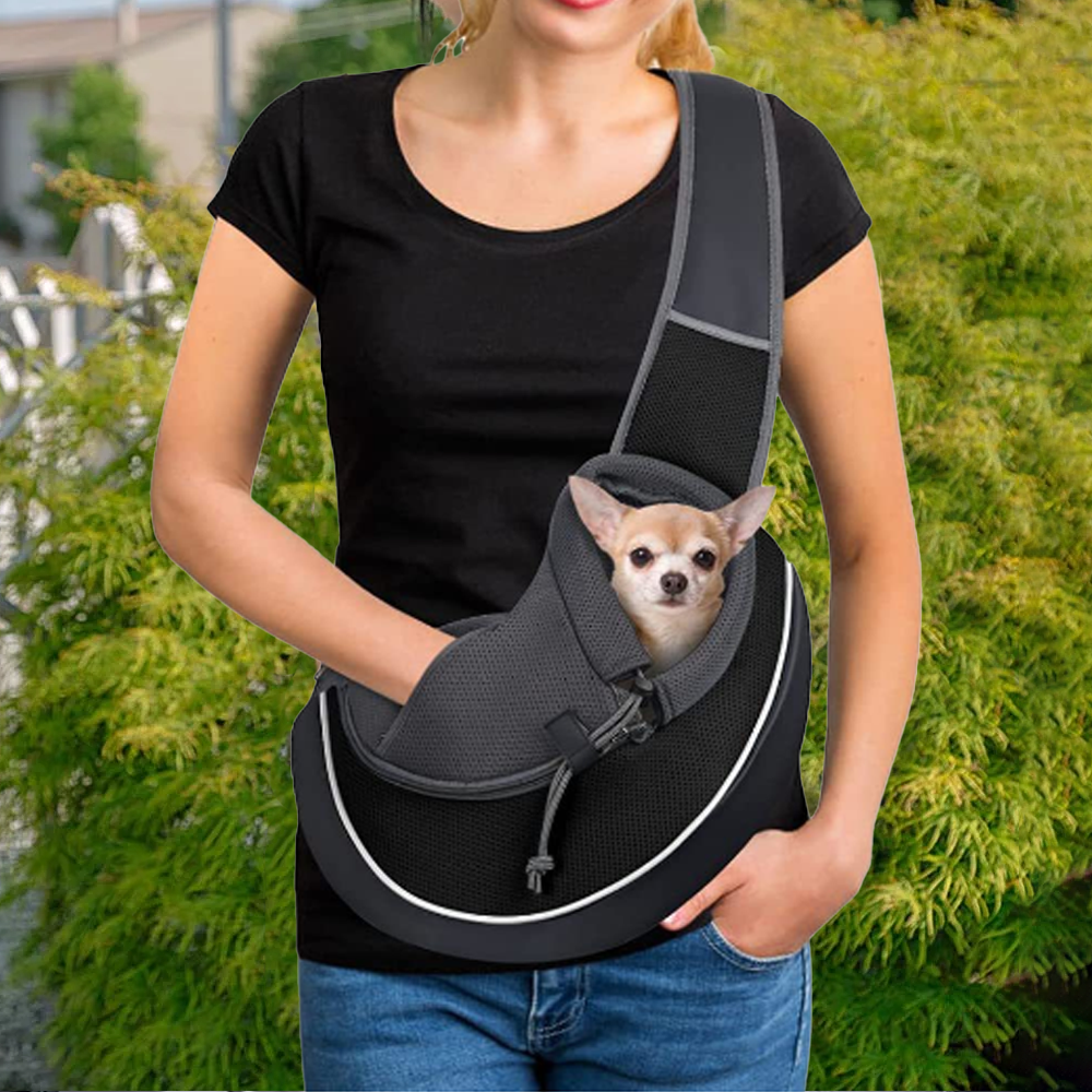 Woman carrying small Chihuahua in black pet sling carrier bag – hands-free travel pouch for small dogs and puppies